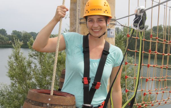 Lachende junge Frau steht an einem Kletterelement