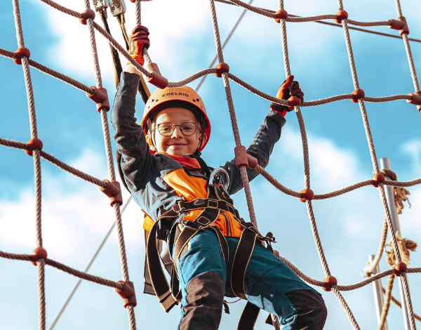 lachendes Kind klettert im Kletternetz