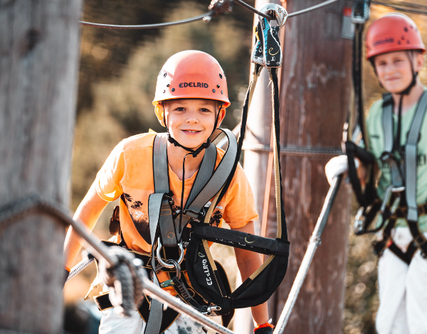 Lchelndes Kind schaut in die Kamera und balanciert in einem Element