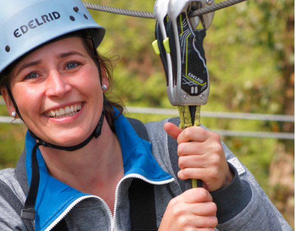 Junge Frau mit Helm und Sicherung lchelt in die Kamera